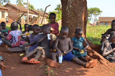 Group of young children sitting in the shade having a drink.